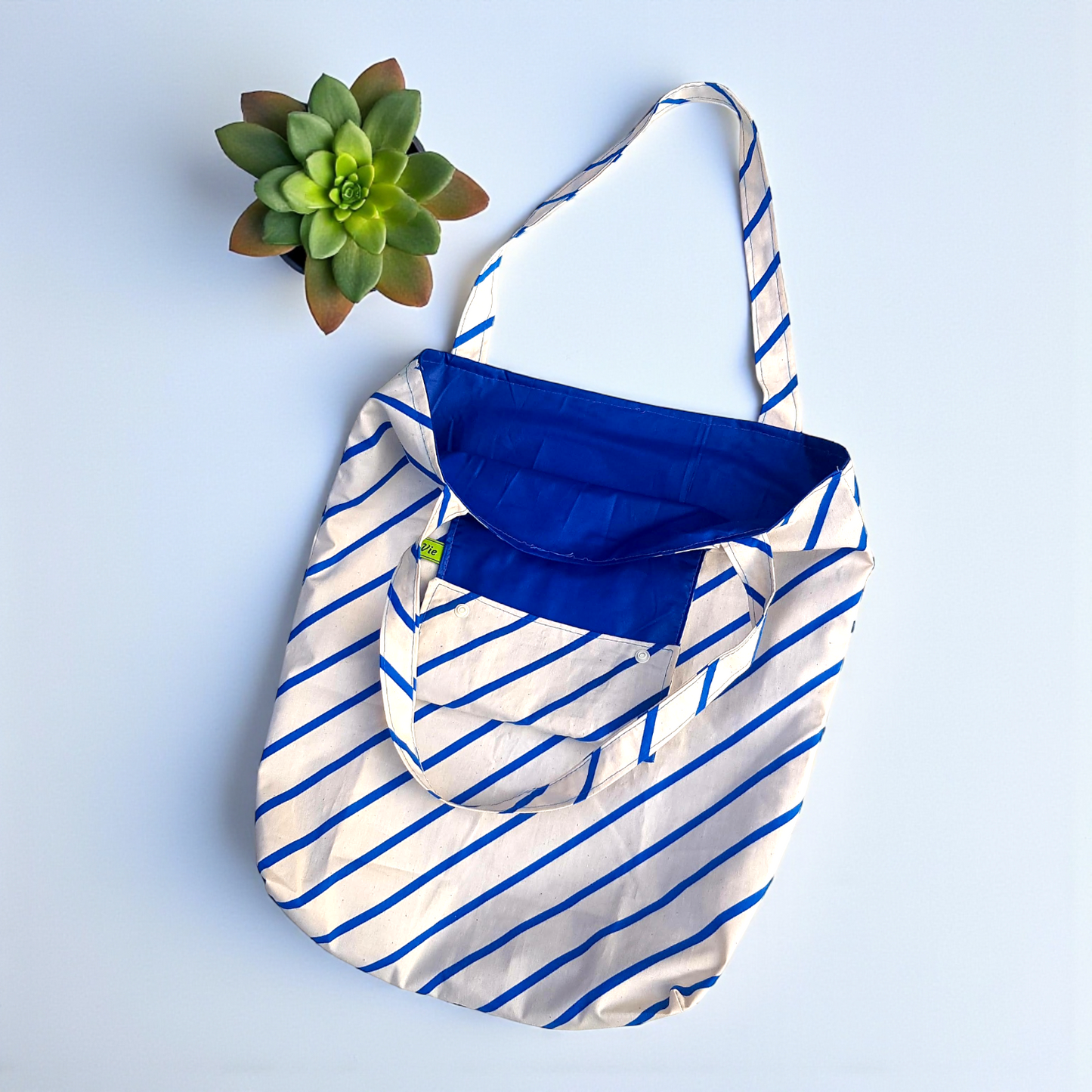 Blue and white striped bag with a blue pocket on a light blue background