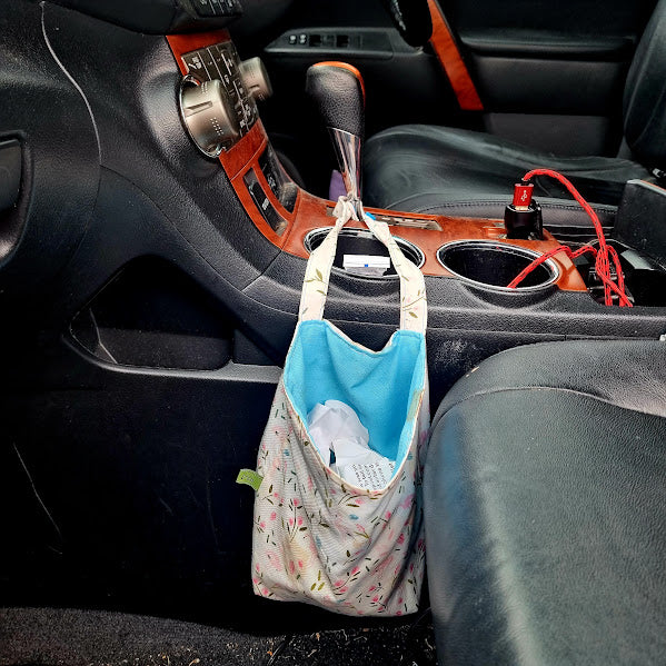 Car organizer hanging from a car centre console with items inside