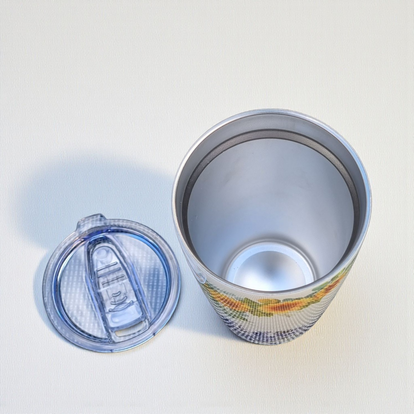 Silver tumbler with colorful design on a white background