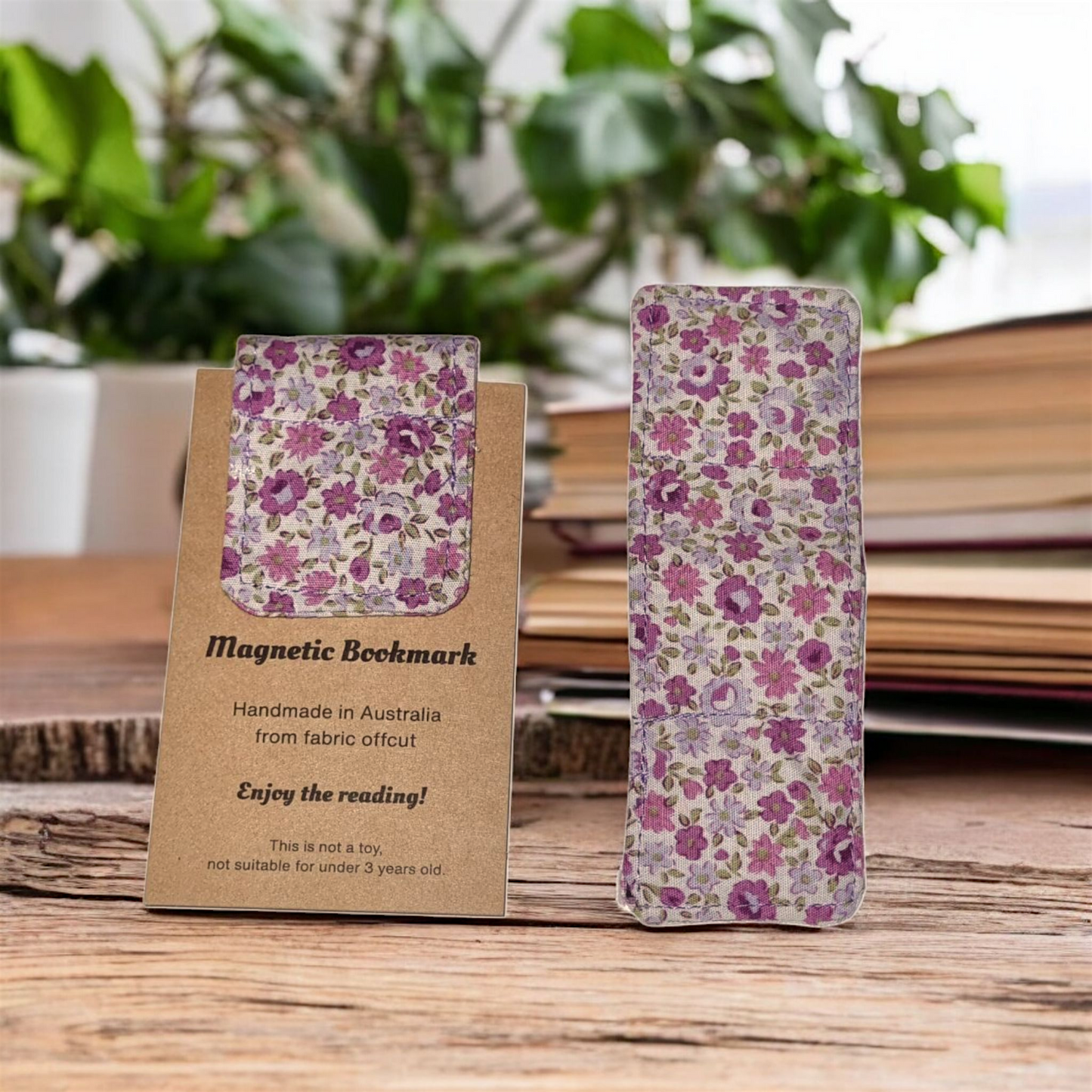 Purple Floral magnetic bookmark on a wooden surface with a plant in the background