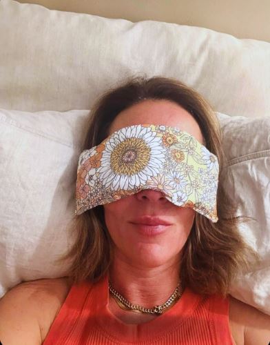 Person wearing a floral sleep mask on a pillow