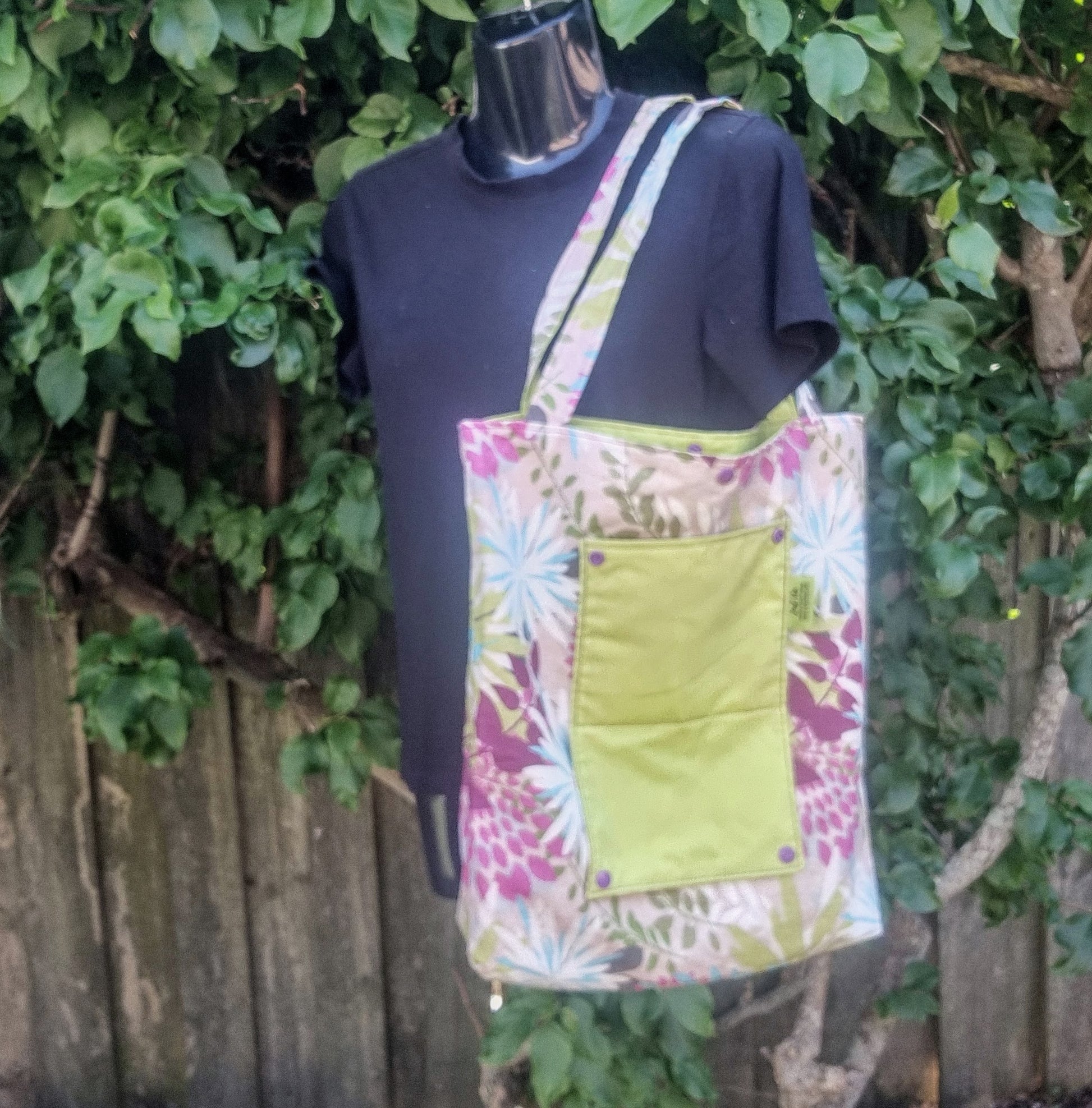 Reusable tote bag in vibrant tropical floral pattern with green pocket.