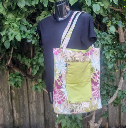 Reusable tote bag in vibrant tropical floral pattern with green pocket.
