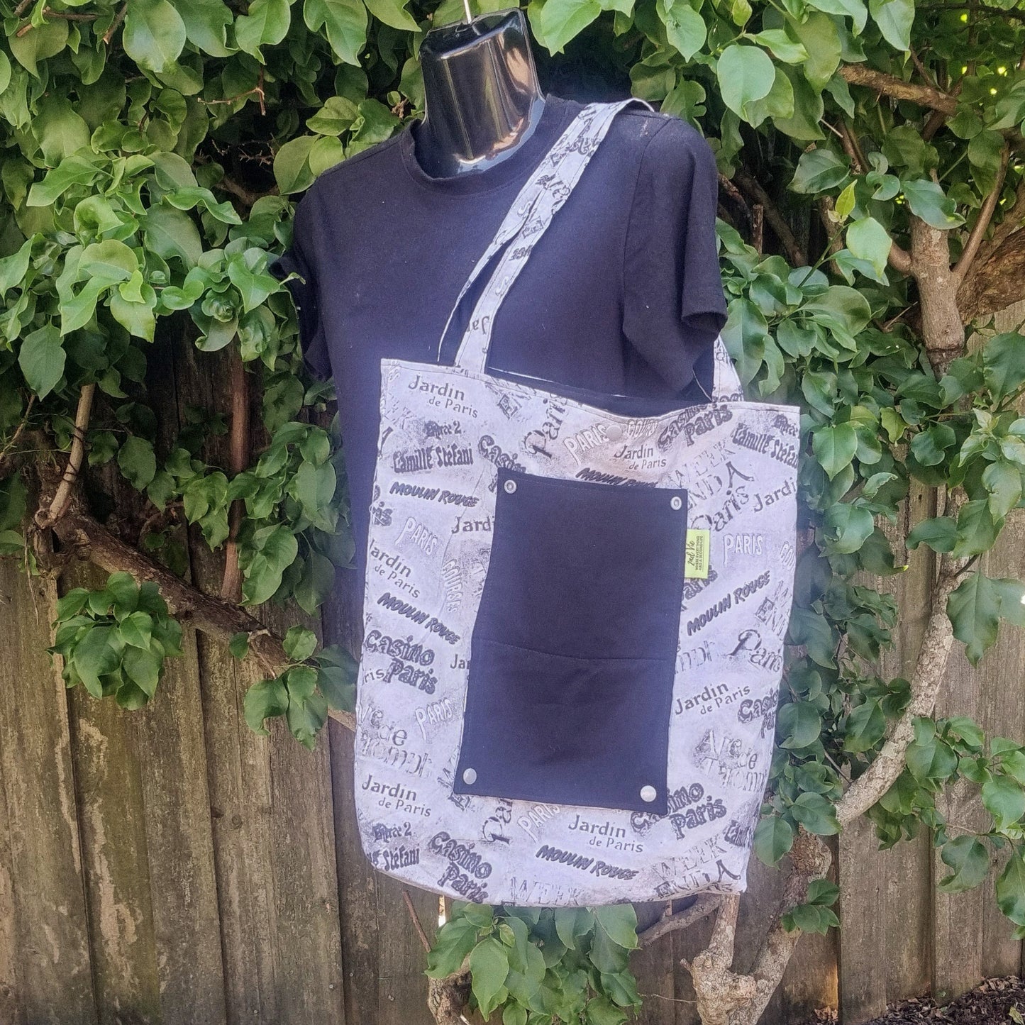 Eco-friendly tote bag in black and white Parisian script print with solid black pocket.