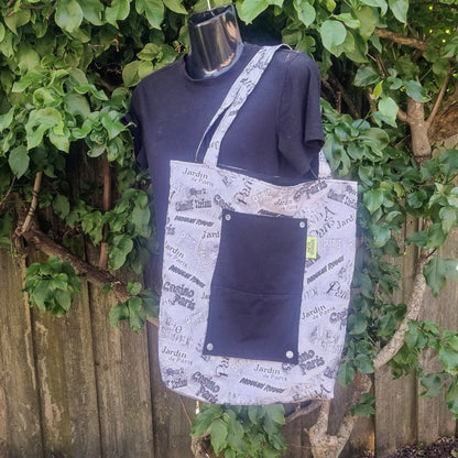 Eco-friendly tote bag in black and white Parisian script print with solid black pocket.