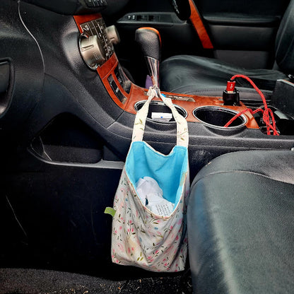 Car organizer hanging from a car centre console with items inside