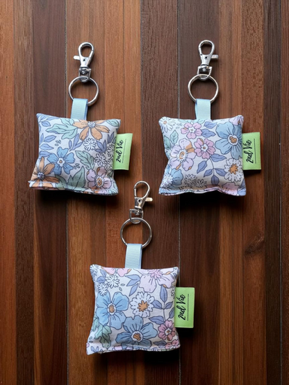 Three floral keychains with tags on a wooden surface