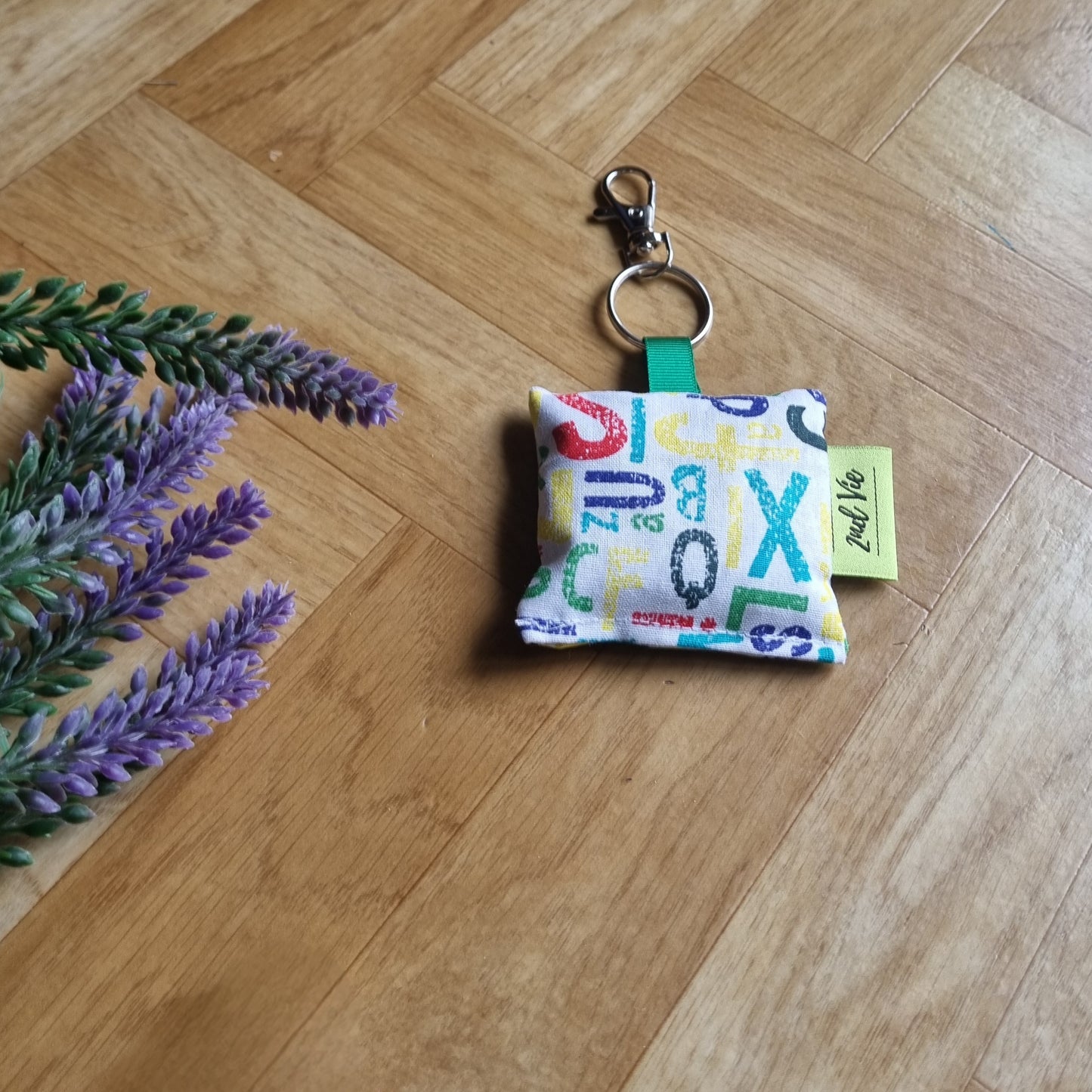 Keychain with colorful letters on a wooden floor with lavender flowers