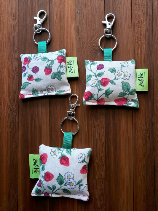 Three Strawberries print with dried lavender keychains with green tags on a wooden surface