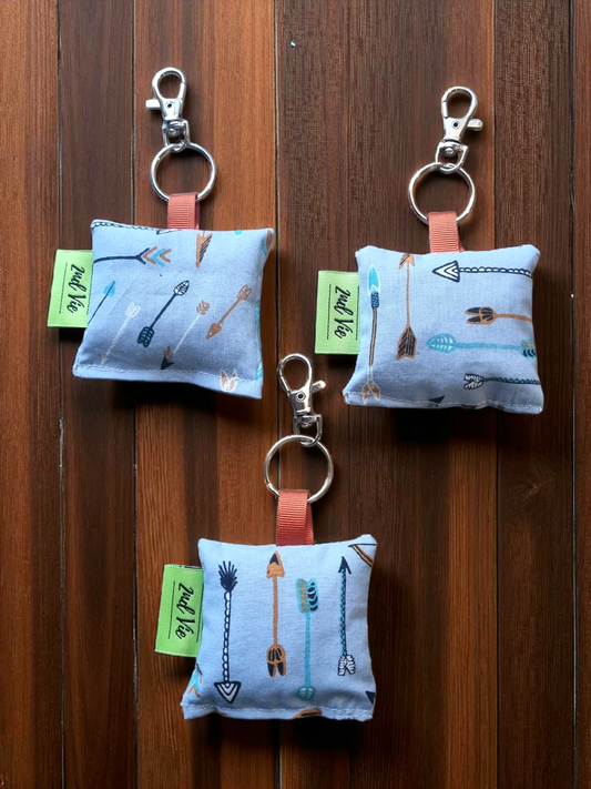 Three small keychains fabric pouches with  arrows design on a wooden surface