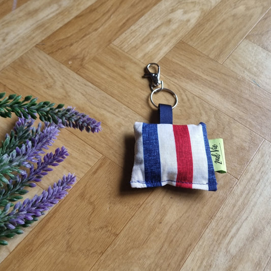 Fabric keychain with red, white, and blue stripes on a wooden floor with lavender flowers.