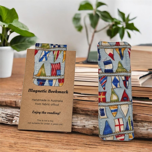 Magnetic bookmark with Different countries flag design on a wooden surface with plants in the background